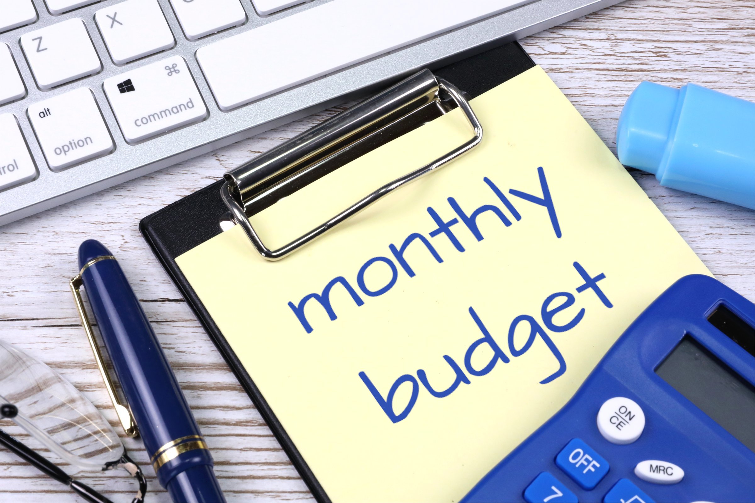 Prancheta com a frase 'monthly budget', caneta e calculadora sobre a mesa